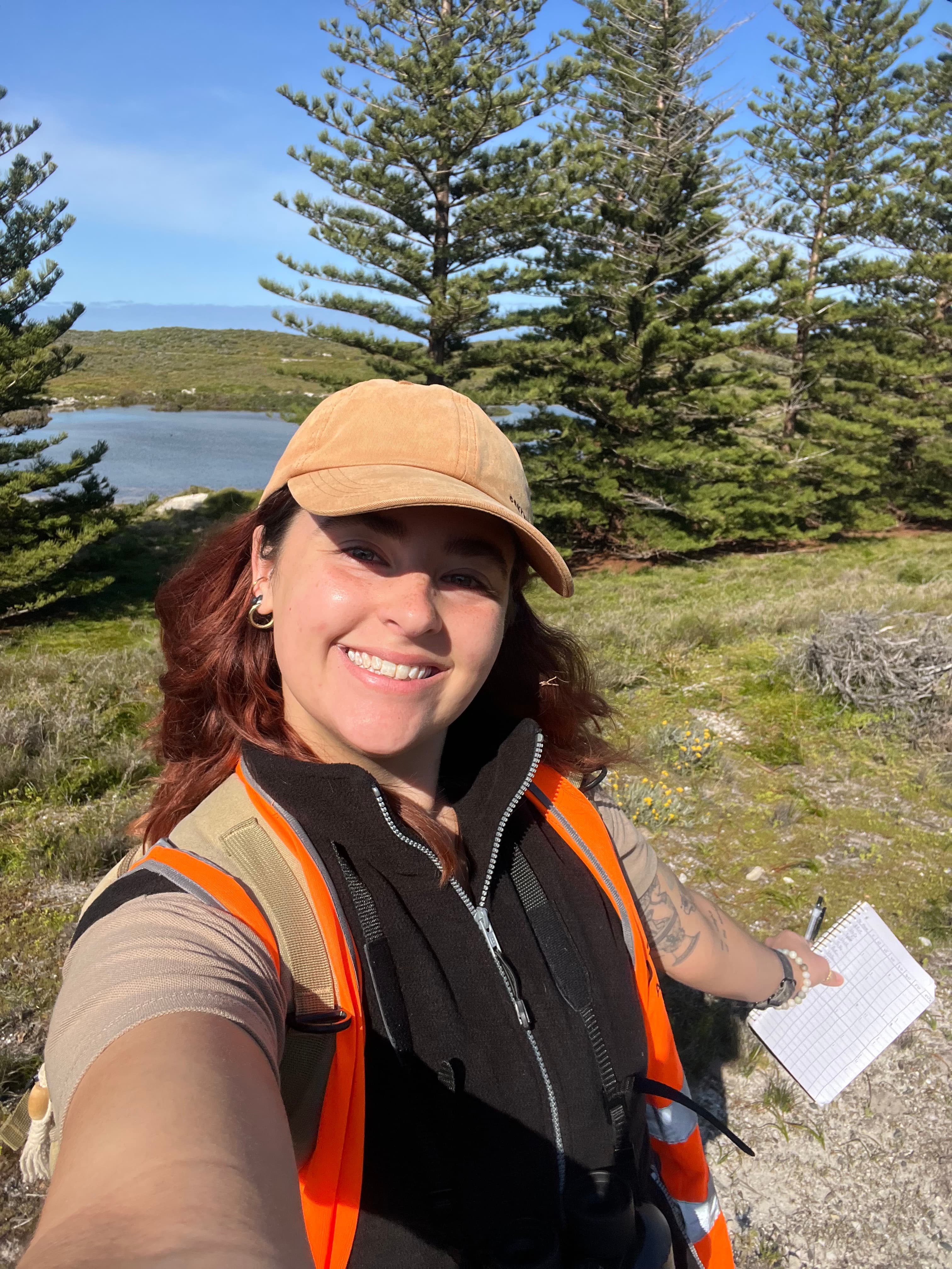A young woman taking a selfie in a nature scenary with a lake shown in the background